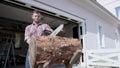 Slow-motion of cutting log with saw. Video. Brutal young man cuts piece of log with saw on background of garage. Sawdust Royalty Free Stock Photo