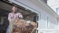 Slow-motion of cutting log with saw. Video. Brutal young man cuts piece of log with saw on background of garage. Sawdust Royalty Free Stock Photo