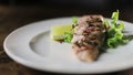 Cooks hand puts a fresh fried red fish steak on white plate and maiking final decoration of dish.