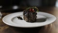 Cooks hand puts a fresh fried steak on white plate and maiking final decoration of dish.