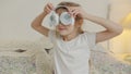 Slow motion of funny little girl listening to music and dancing in bed hoilding headphones as eyes
