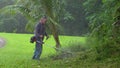 Slow motion of a gardener weed whacking the grass and the lawn in tropical Hawaii