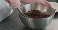 Slow motion handheld shot of whisking cream with chocolarte in steel bowl