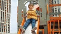 Slow motion of happy cheerful boy sliding down the slide at new playground. Active child, sports and development, kids playing Royalty Free Stock Photo