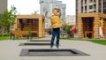 Slow motion of little boy jumping and having fun on trampoline in new park at city block. Active child, sports and development, Royalty Free Stock Photo