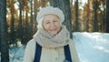 Slow motion portrait of attractive senior lady in winter clothes ourdoors in park in winter smiling