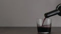 Slow motion pour red wine into tumbler glass on wood table with copy space Royalty Free Stock Photo