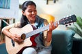 Slow motion shot of Happy Women enjoy singing by playing Guitar while sitting on sofa at home - Concept of Learning, practicing