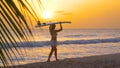 SLOW MOTION: Unrecognizable woman carries a surfboard on her head at sunset. Royalty Free Stock Photo