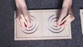 Female hands drawing lines in two-sided wooden stencil labyrinth