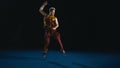 Young man training wushu against black background