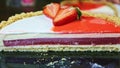 Slow panorama down at half of cheesecake with red jelly interlayer and colorful icing