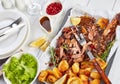 Slow roast ultra tender shoulder of lamb pulled off the bones with crispy roast potatoes on a baking ray on a wooden table with Royalty Free Stock Photo