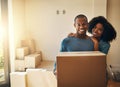 We are slowly getting there. Portrait of a cheerful young couple standing together while holding a cardboard box on