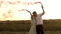 Slowmo of man and woman who are standing in field and waving smoke bombs on gender reveal party