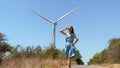 Slowmotion shot. Young woman visits a wind turbine farm in a semidesert environment. Wind energetics concept