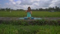 Slowmotion steadicam shot of a young woman doing meditation for Muladhara chakra in a Balinese way