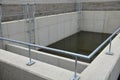 Sludge, retention sump, concrete tank divided by a partition. two control galvanized metal ladders lead into the water. rainwater Royalty Free Stock Photo