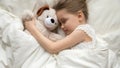Slumber kid embrace stuffed toy sleeping in bed top view