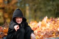 Sly boy in a black hooded jacket sits on the curb and smiles Royalty Free Stock Photo