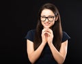 Sly concentrated happy business woman in glasses looking in camera and plotting new earring solution and fingering on black