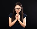 Sly concentrated happy business woman in glasses looking in camera and plotting new earring solution and fingering on black