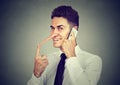 Sly young man with long nose talking on mobile phone on gray wall background. Liar concept. Royalty Free Stock Photo