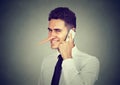 Sly young man with long nose talking on mobile phone on gray wall background. Liar concept. Royalty Free Stock Photo