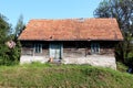 Small abandoned old wooden family house with dilapidated boards and missing roof tiles on top of small hill surrounded with grass Royalty Free Stock Photo