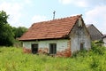 Small abandoned ruined brick house surrounded with tall uncut grass Royalty Free Stock Photo