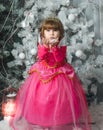 Small adorable female child in pink dress holds snow in his hands, New Year`s decorations