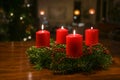 Small Advent wreath from fir branches with red burning candles and a simple Christmas chain on a dark wooden table, living room Royalty Free Stock Photo