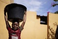 Small African Girl Carrying Home a Big Water Bucket On Her Head Royalty Free Stock Photo