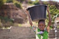 Small African Girl Returning Home From The Village Borehole With a Huge Water Bucket
