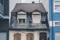 Small aged and old house between two modern and new houses