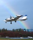 Small aircraft landing with rainbow sky