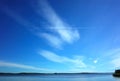 Small airplane flying with trail on background of beautiful light clouds on blue sky Royalty Free Stock Photo