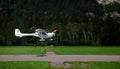 Small airplane landing on a landing strip near forrest