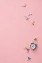 Small alarm clock and fasteners on pink background, flat lay, top view.