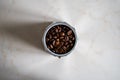 Small aluminum cup full of dark coffee beans