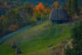 Small ancient barn house on a hill with a road passing by and haystacks in the foreground with a forest in the background Royalty Free Stock Photo