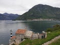 A small ancient church hiding beyond the curve of a Kotor harbour in Montenegro Royalty Free Stock Photo