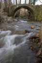 Small ancient stone bridge over mighty river in Valle del Ambroz Extremadura in vertical