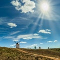 Small ancient windmills under the rays of the sun in a deep blue sky with white clouds. La Mancha Spain Royalty Free Stock Photo