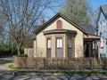 Tan Corner Cottage with Natural Wooden Picket Fence