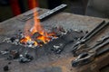 A small anvil, forge and blacksmith tools.