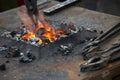 A small anvil, forge and blacksmith tools.