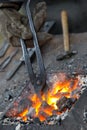 A small anvil, forge and blacksmith tools.