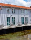 Small apartment building by the sea. Wooden chairs and tables on the deck by the water