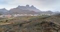 Small arabian village in arid desert with mountains in the back. View from the entrance of Al Hoota cave in Oman. Hazy